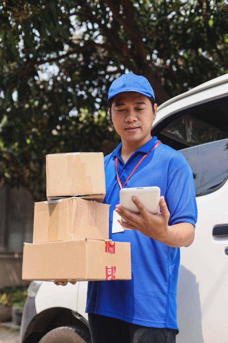 courier-checking-smartphone-while-bring-pile-of-ca-2022-09-14-20-09-26-utc
